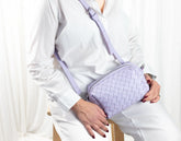 Person holding a lavender woven handbag against a white background