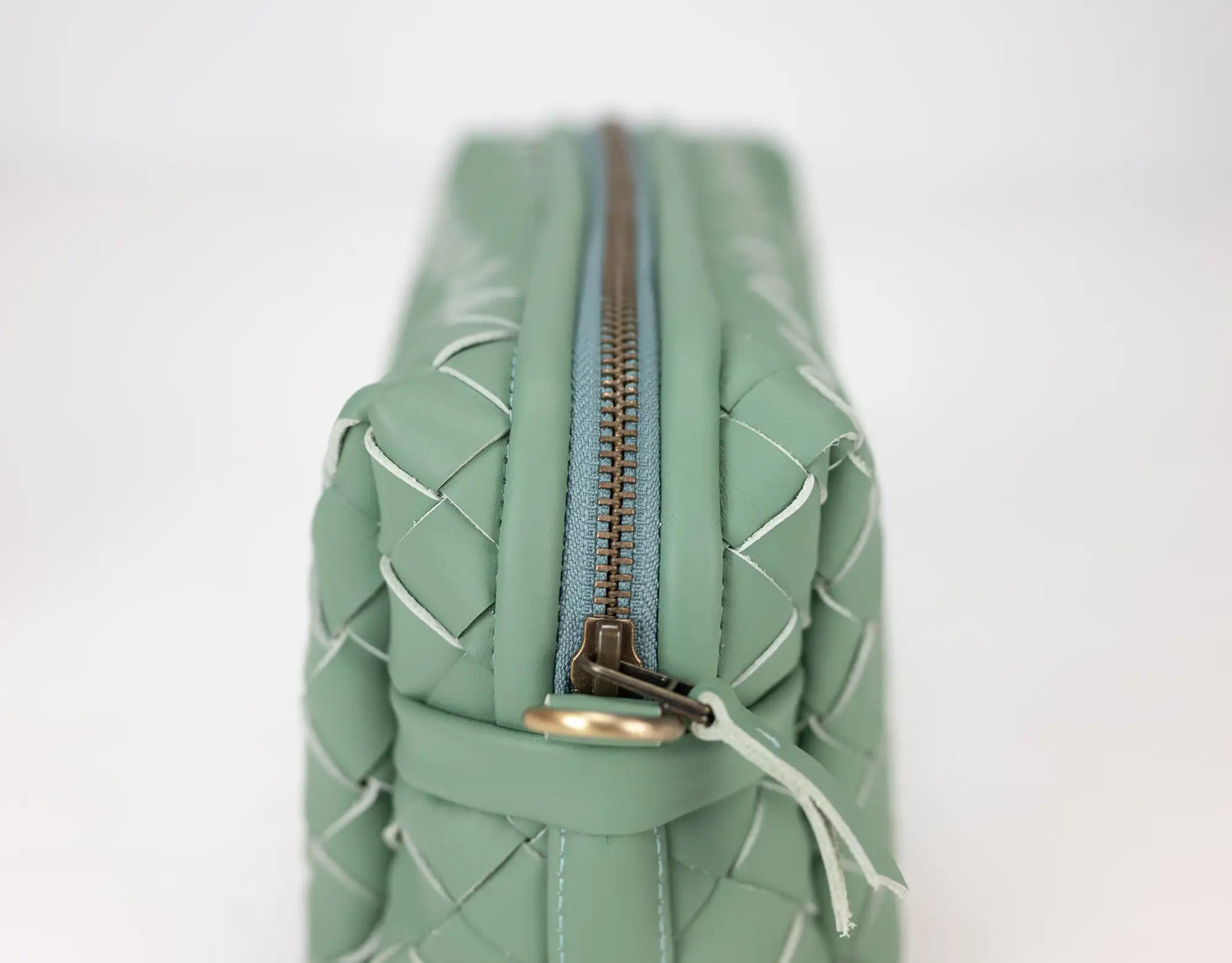 Green woven bag with a zipper on a white background