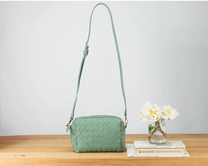 Green quilted handbag on a wooden surface with a white background