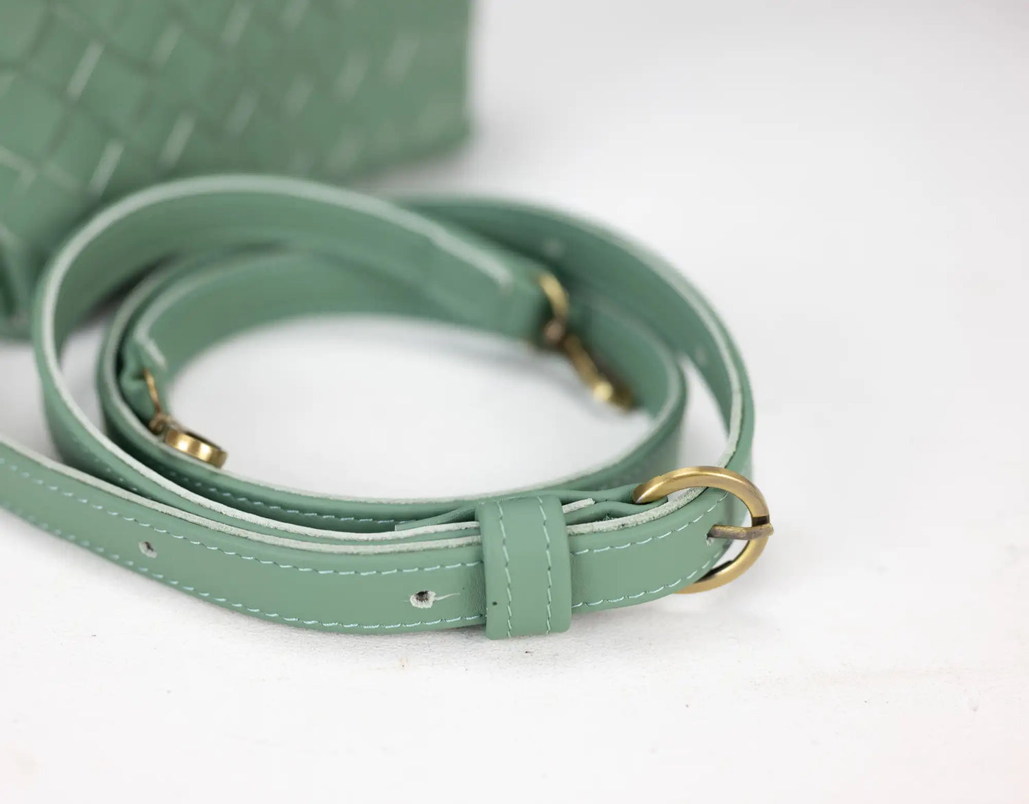 Green leather belt with gold hardware on a white background