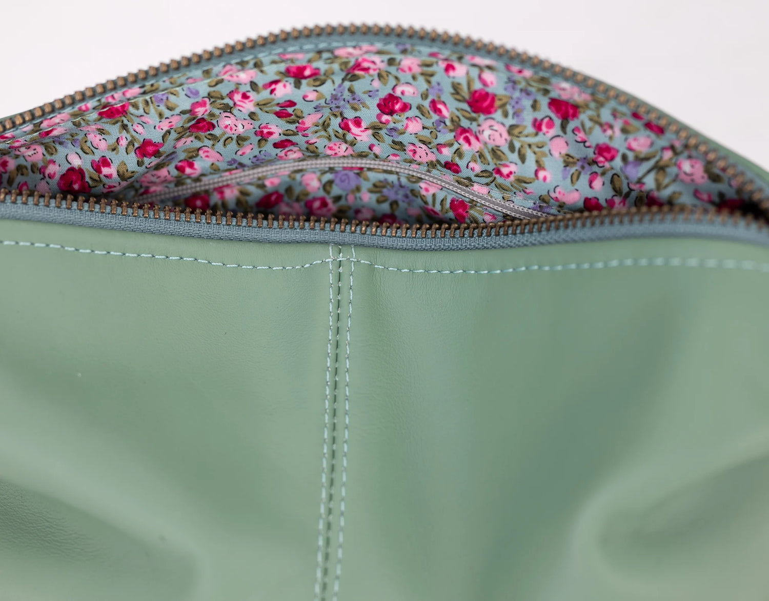 Close-up of a green fabric pouch with floral patterned flap.