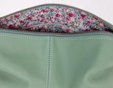 Close-up of a green fabric pouch with floral patterned flap.
