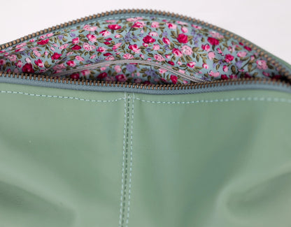 Close-up of a green fabric pouch with floral patterned flap.
