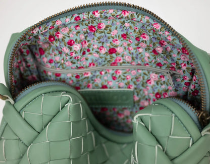 Green woven handbag with floral interior on a white background