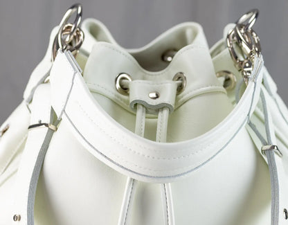 Close-up of a white leather handbag with silver hardware on a gray background