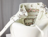 White handbag with floral patterned interior on a gray background