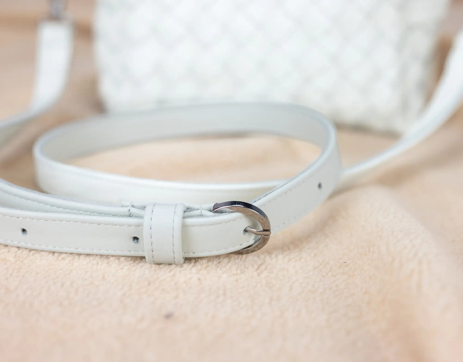 White leather belt on a beige surface