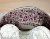 Floral-patterned fabric inside a white zipper pouch on a wooden surface