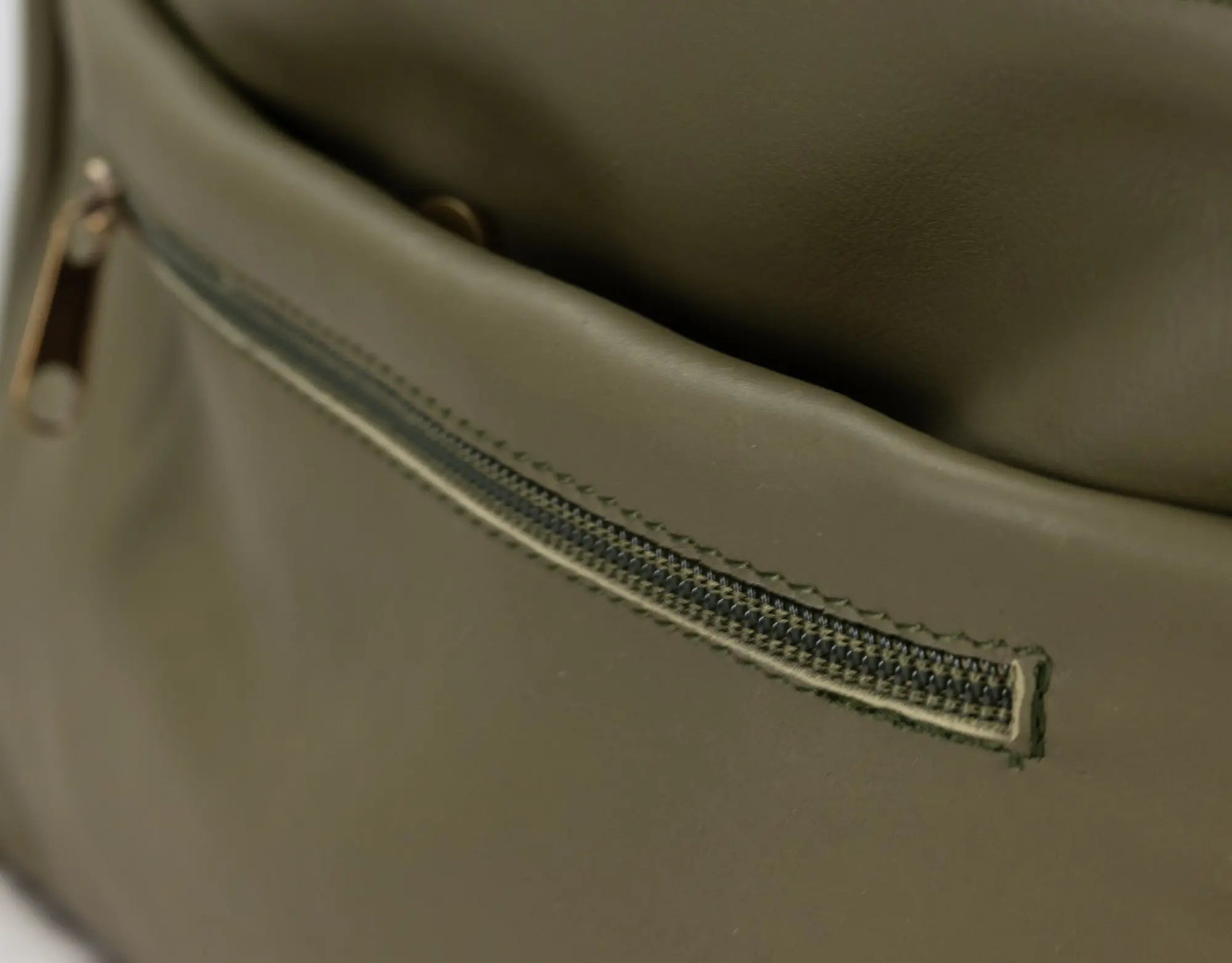 Close-up of a green leather bag with a zipper.