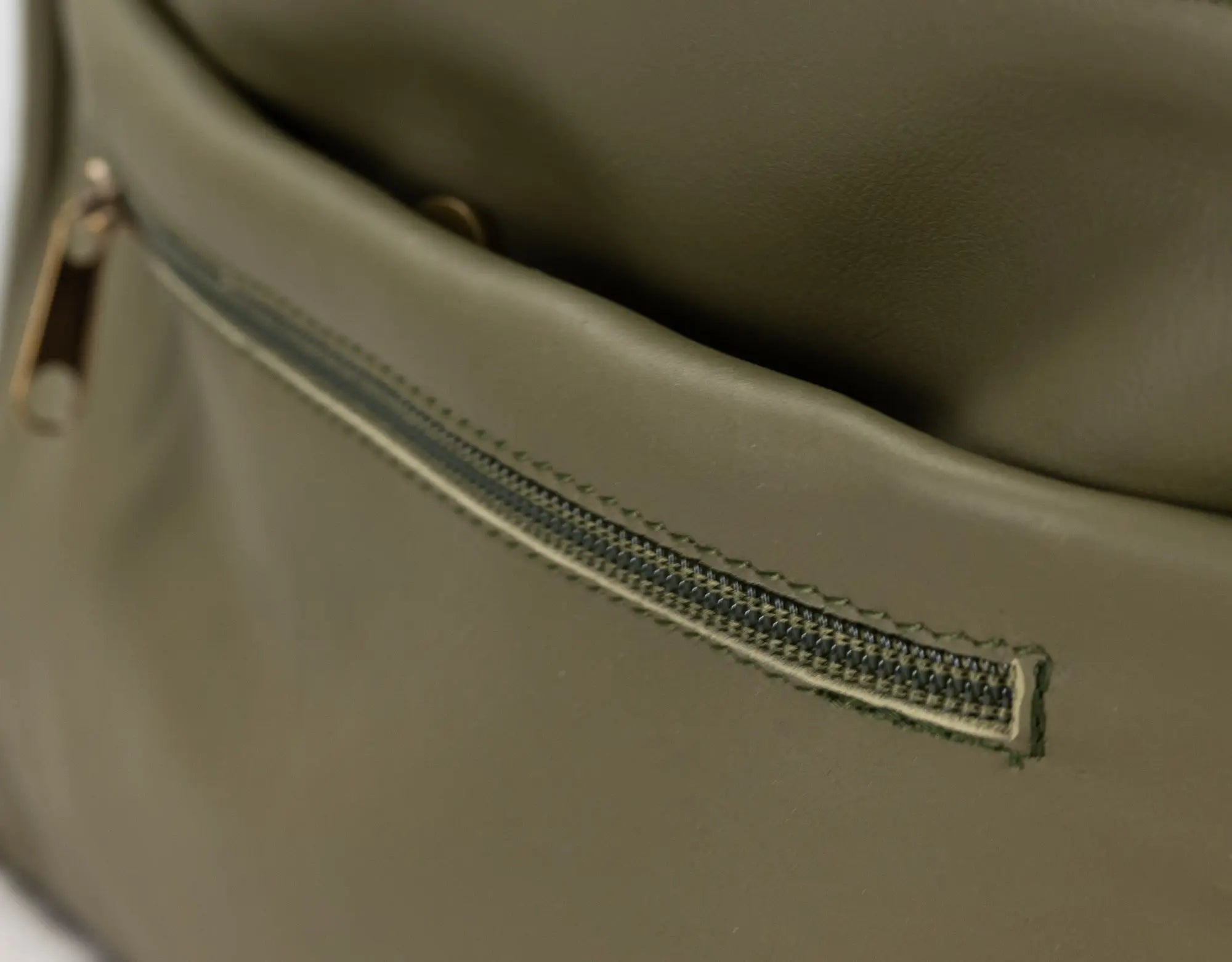 Close-up of a green leather bag with a zipper