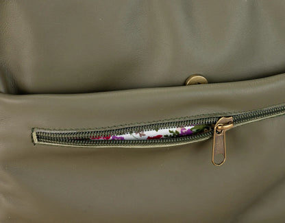 Close-up of a green leather bag with a zipper pocket showing floral lining.