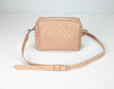 Beige woven handbag with a strap on a light gray background