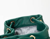 Close-up of a green leather bag with gold eyelets on a white background