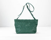 Green textured handbag with a strap on a white background