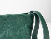 Green woven handbag with a strap on a white background