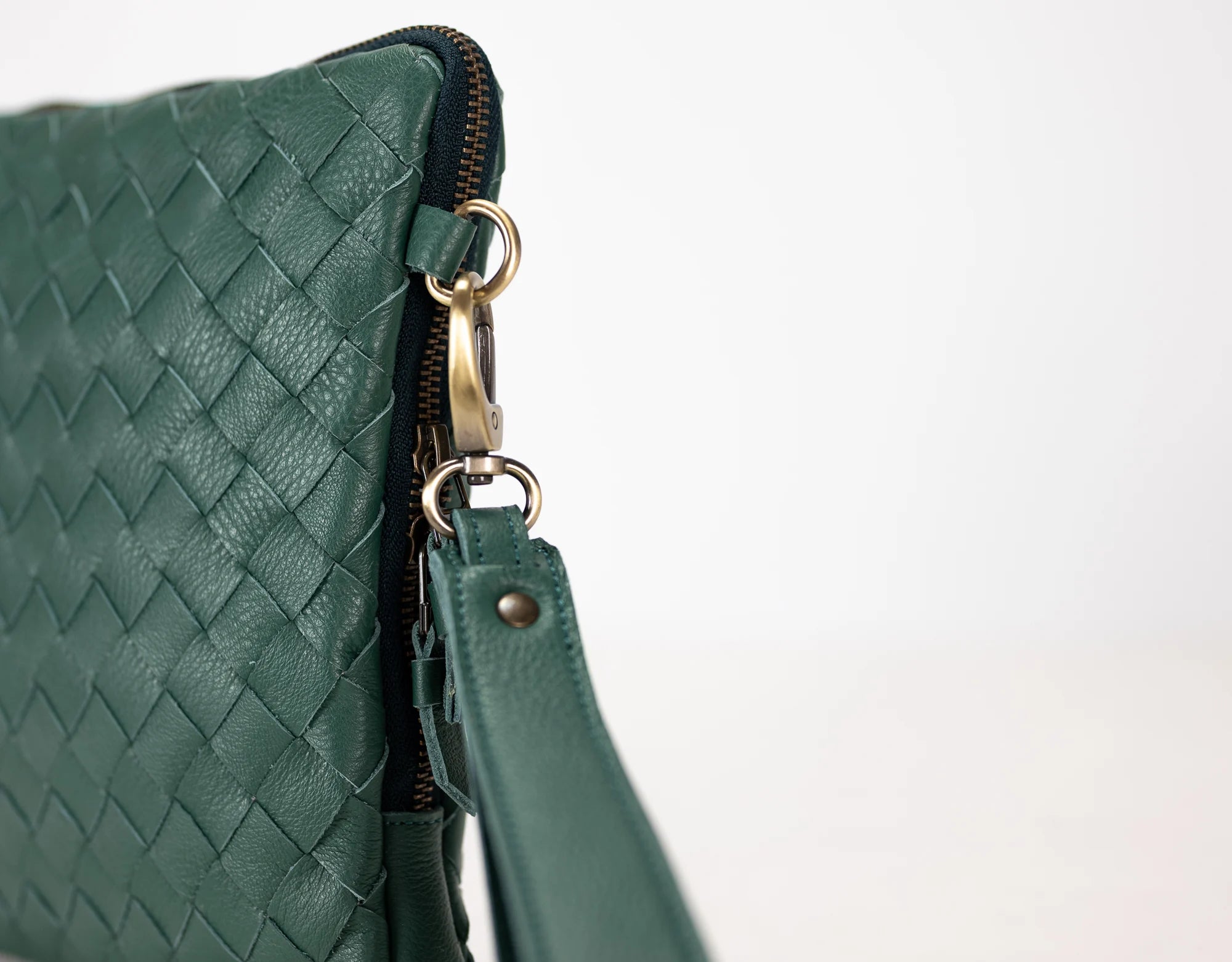 Green woven leather handbag with gold zipper on a light gray background