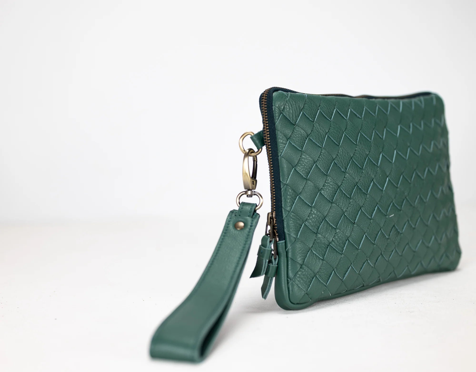 Green woven clutch bag with wrist strap on a white background