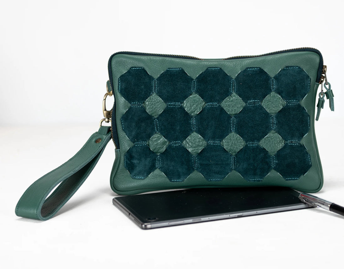 Green quilted clutch bag with a phone and pen on a white background