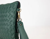 Green woven leather handbag with gold zipper on a light gray background