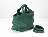 Green textured handbag with matching strap on a white background