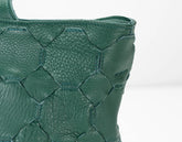 Close-up of a green textured handbag on a white background