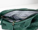 Green leather handbag with gold zipper on a white background