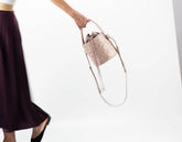 Person holding a beige handbag with a white background