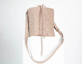 Beige quilted handbag with drawstring on a light gray background