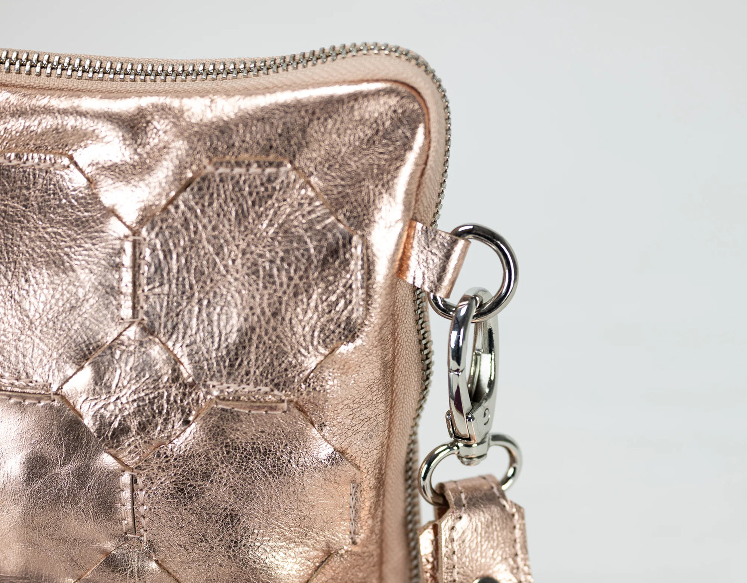 Rose gold metallic wallet with a chain detail on a light gray background