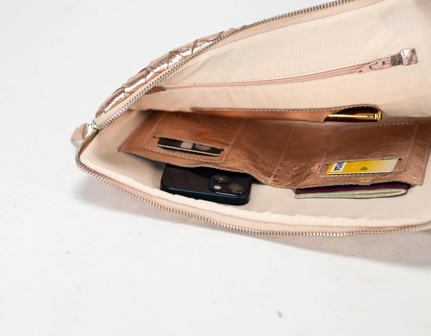 Beige clutch bag with a brown wallet and phone inside on a white background