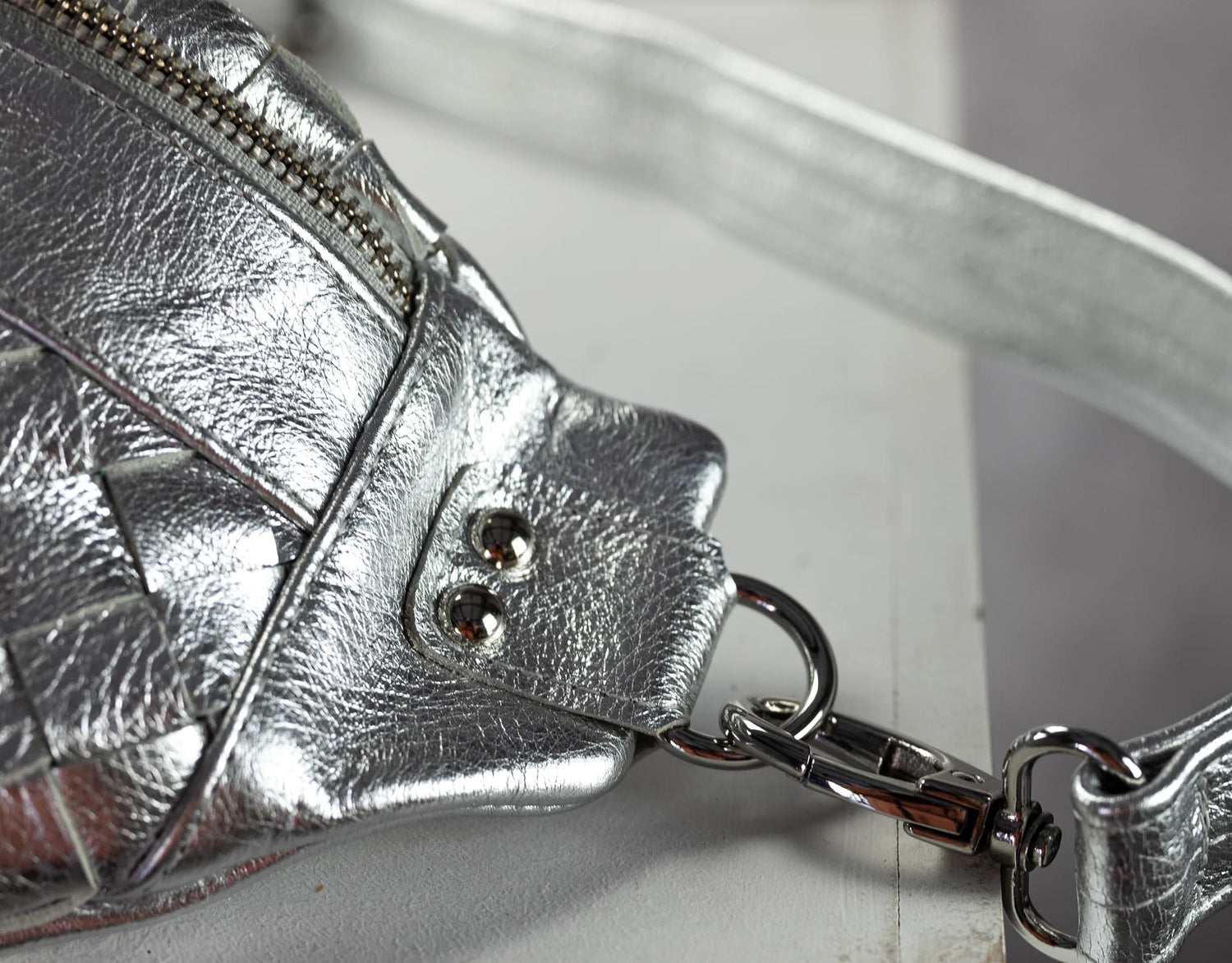 Close-up of a silver leather handbag with a strap on a white background