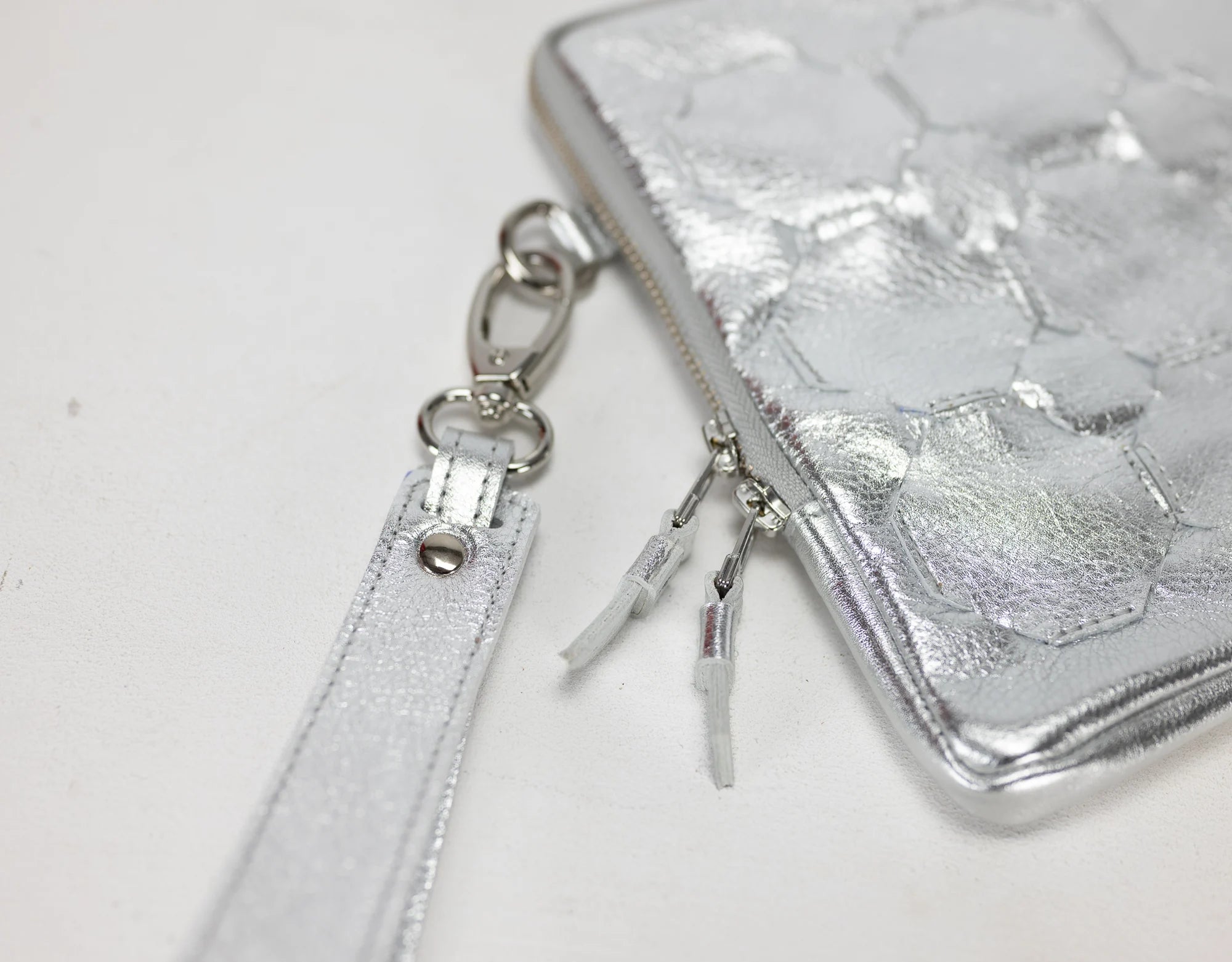 Silver wallet with strap and keychain on a white background
