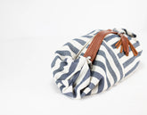 Striped fabric roll with brown leather strap on a white background