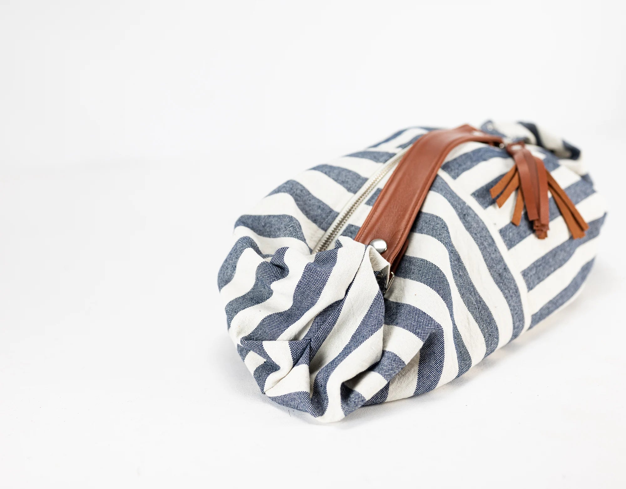 Striped fabric roll with brown leather strap on a white background