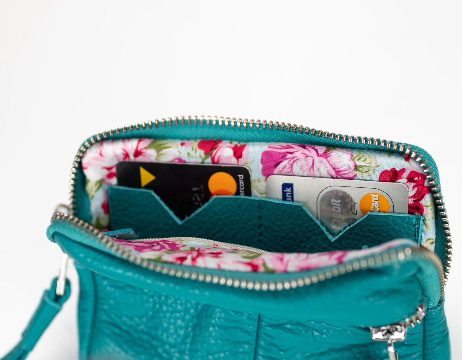Teal handbag with floral interior showing credit cards on a white background