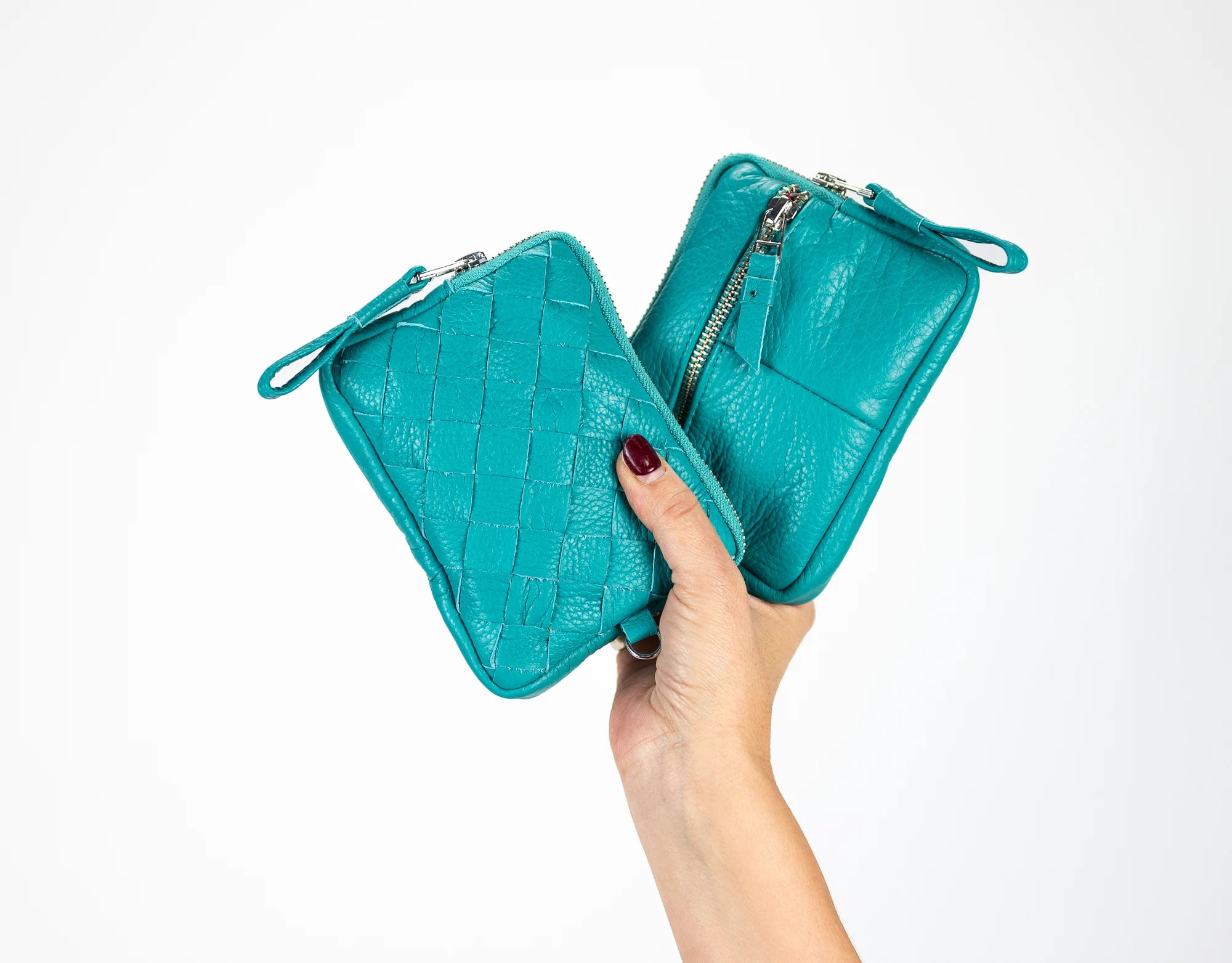 Turquoise leather clutch held by a hand on a white background