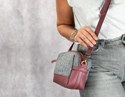 Person holding a small pink handbag with a textured pattern against a neutral background