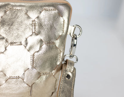 Close-up of a gold textured handbag with a chain detail on a light gray background