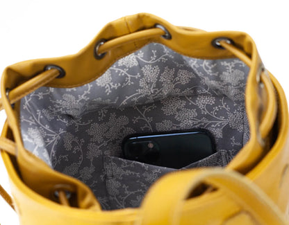 Yellow leather bag with floral patterned interior showing a phone inside.