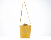 Yellow quilted handbag with a strap on a white background