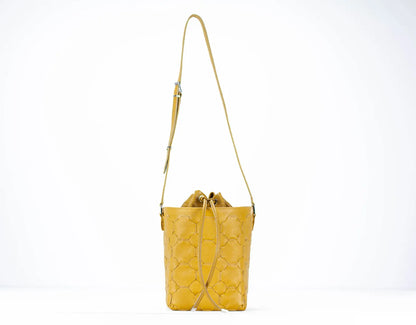 Yellow quilted handbag with a strap on a white background