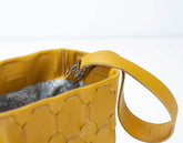 Yellow handbag with textured surface and strap on a white background