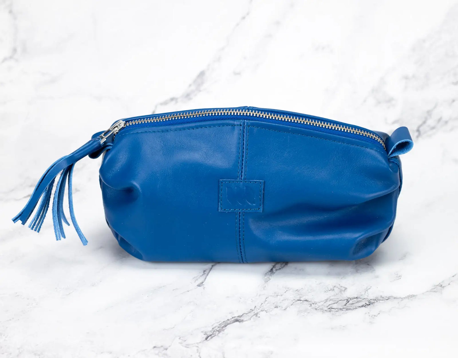 Blue leather pouch with a tassel on a marble surface#color_royal-blue