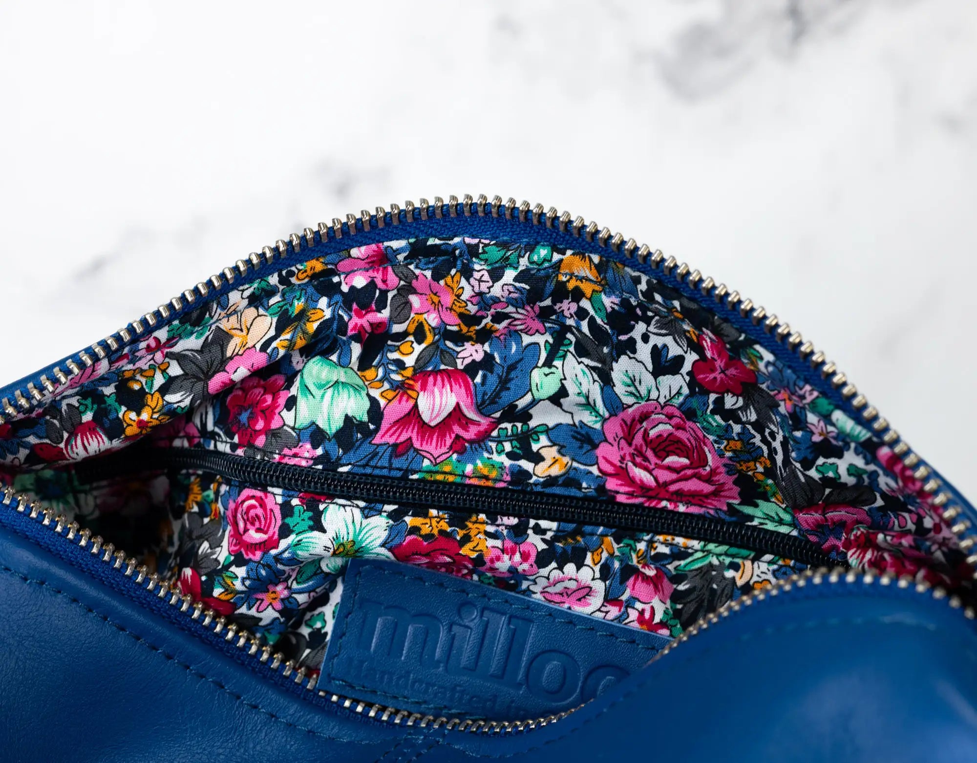Blue pouch with floral pattern and visible brand name on a white background