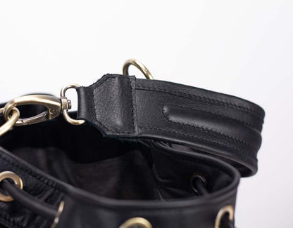 Close-up of a black leather bag with gold hardware on a white background