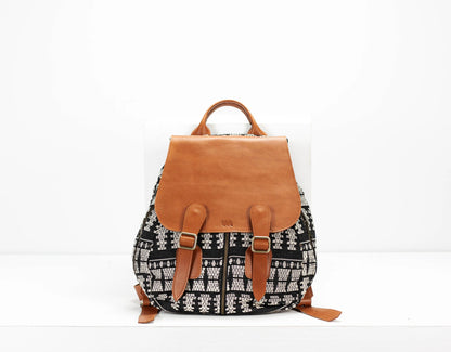 Backpack with black and white pattern and brown leather straps on a white background