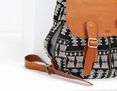 Black and white patterned bag with brown leather straps on a white background