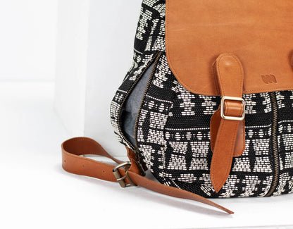 Black and white patterned bag with brown leather straps on a white background