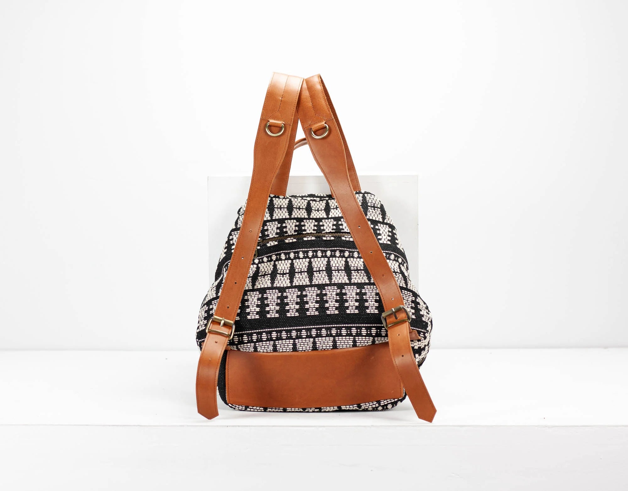 Backpack with brown straps and black and white pattern on a white background