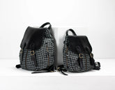 Two backpacks, one with a houndstooth pattern and the other black, on a white background.